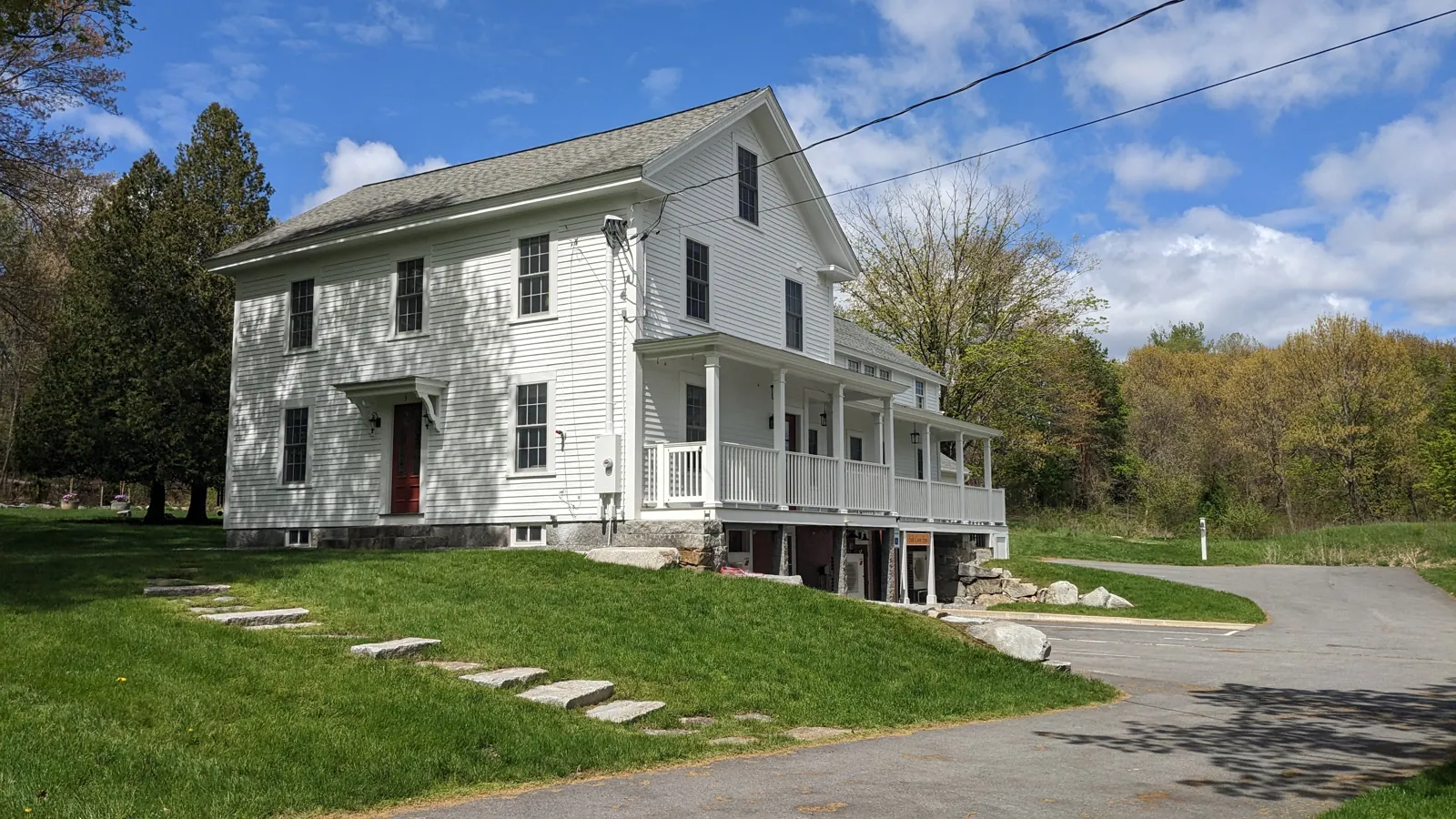 White farmhouse with a wraparound porch painted by Beacon